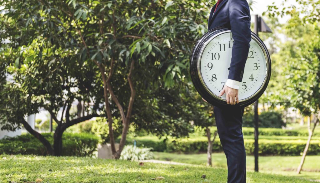 mężczyzna stoi w parku i trzyma zegar